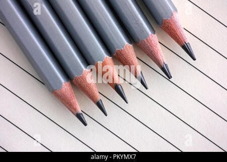 Grau graphit Bleistift in einer Reihe auf liniertem Papier Hintergrund. Stockfoto