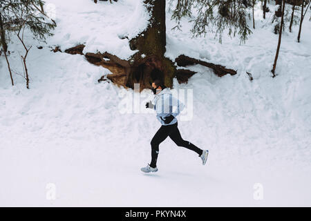 Seitenansicht des jungen Athleten laufen durch den Park, das Tragen von Training Maske Stockfoto