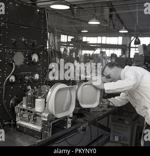 1950 s, historischen, weiß beschichteten männlichen Techniker auf den Komponenten der Fernsehgeräte in der Fabrik von Bush Radio, einem führenden britischen consumer electronics Unternehmen in dieser Zeit zu arbeiten. Stockfoto