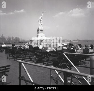 1950, historische, Passagiere auf einem Schiff in den Hafen von New York die Close-up, um zu sehen, die Freiheitsstatue. Vom Hudson und East Flüsse meeet, Lower Manhattan, New York, USA. Der klassizistische Skulptur, die ein Geschenk der Freundschaft von der Französischen an die Völker der USA und von berühmten französischen Bildhauer Bartholdi gebaut, zusammen mit dem Ingenieur, Gustave Eiffel, er der legendären Pariser Turm. Stockfoto