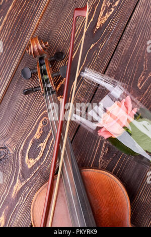 Violine und rosa Rose auf Holz- Hintergrund. Stockfoto