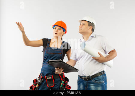 Ein Architekt Mann mit einem harten Hut oder Helm und Co-worker builder Frau überprüfung Blueprints Stockfoto