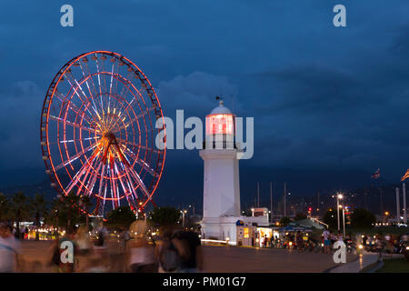 Nacht Blick auf die beleuchtete Riesenrad und Leuchtturm in Batumi, Georgien Stockfoto