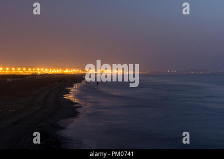 Lange Belichtung Landschaft wenig Licht Foto der Strand in Valencia in Spanien in den frühen Morgen mit den Lichtern der Stadt im Hintergrund Stockfoto