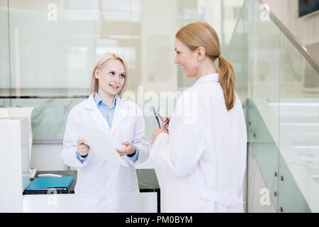 Zwei Ärzte in whitecoats diskutieren Beschreibung der neue kosmetische oder medizinische Produkte Stockfoto