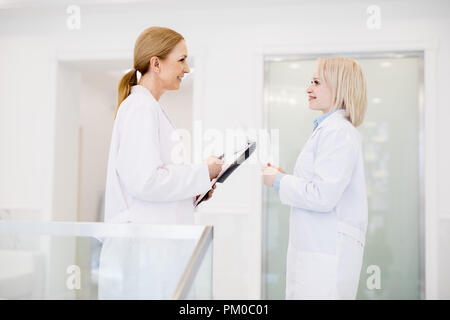 Zwei weibliche Ärzte in Arbeitskleidung in Sprechen über neue medizinische Geräte, die bald ausgeliefert werden. Stockfoto