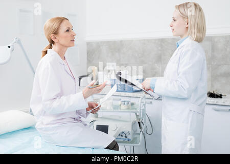 Zwei Fachärzte in whitecoats Diskussion über die Wirksamkeit der neuen Medizin oder medizinische Behandlung in der Sitzung Stockfoto