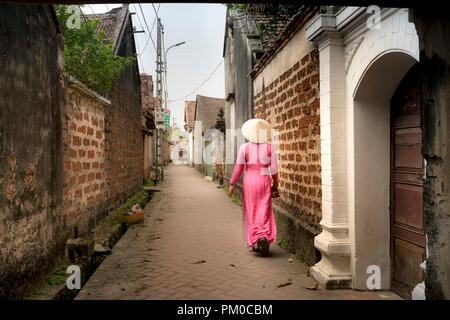 Eine charmante Frau, die in einem traditionellen Ao Dai im alten Dorf Duong Lam. Ha Noi, Vietnam Stockfoto