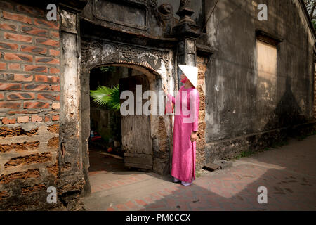 Eine charmante Frau, die in einem traditionellen Ao Dai im alten Dorf Duong Lam. Ha Noi, Vietnam Stockfoto