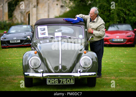 Ein Mann wischt Regen von seinem Volkswagen Käfer nach einer Dusche auf ein klassisches Auto-Versammlung in Sudeley Castle in den Cotswolds. Stockfoto