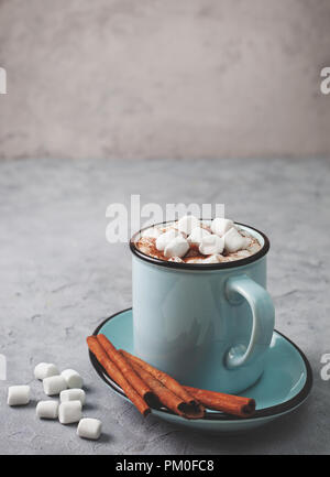 Heiße Schokolade mit Marshmallows in einem blauen Becher auf grauem Stein Hintergrund Stockfoto