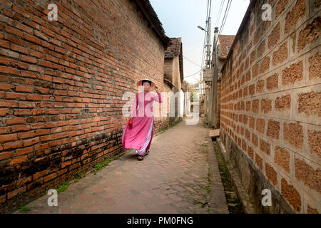 Eine charmante Frau, die in einem traditionellen Ao Dai im alten Dorf Duong Lam. Ha Noi, Vietnam Stockfoto