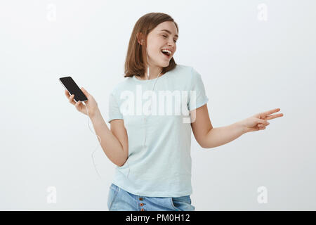 Mädchen zu wirklichen Stern mit perfekter Klang der Ohrhörer. Portrait von uns glücklich und nette Frau Tanzen singen Musik hören Songs in Ohrhörer holding Smartphone Stockfoto