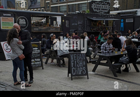 London, England. 15. September 2018. Garküche Verkauf von veganen Fisch und Chips. meist junge Menschen essen im Freien an Tischen, ein Paar Umarmung in der für Stockfoto