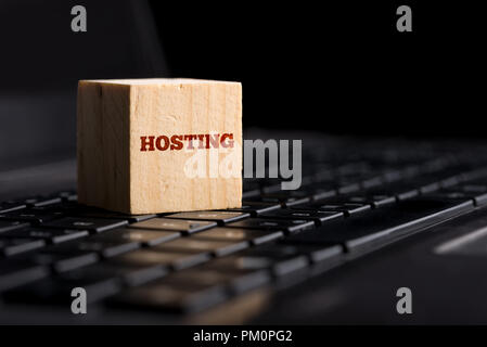 Computer Hosting und Internet Provider Konzept mit dem Wort - Hosting - auf einen Holzblock auf einer PC-Tastatur über einen dunklen Hintergrund mit Stockfoto