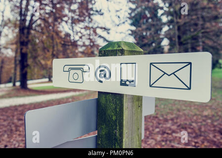 Retro Vintage Style Bild eines Kontakt Namensschild mit Symbolen für Telefon, E-Mail und mobile im Freien in einem Herbst Park. Stockfoto