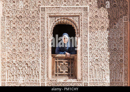 26-02-15, Marrakesch, Marokko. Eine Frau in der traditionellen Kleid sieht durch ein Fenster der Medersa Ben Youssef, oder der Sohn von Joseph an der Schule. Foto © Sim Stockfoto