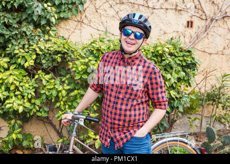 Glückliche junge männliche halten bycycle Hintergrund grün Stockfoto