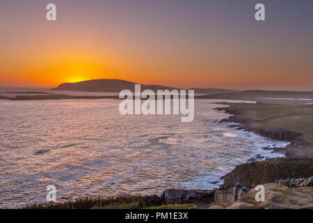 Die Sonne hinter dem Ness von Burgi an der südlichen Spitze von Shetland, wie von Sumburgh Head gesehen. Stockfoto