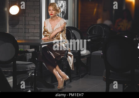 Einsame Dame an der Bar sitzt hinter leere Tabelle. Die menschlichen Beziehungen - Verrat und Täuschung Stockfoto