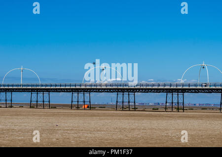 SOUTHPORT, Großbritannien, 8. Juli 2018: ein Foto dokumentation P-51 Mustang Vintage Aircraft flying low über Southport Pier und Strand in blauer Himmel bei Southport Stockfoto