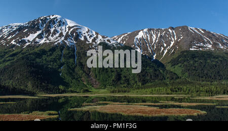 Die flachen Gewässern der Tern See in Alaska spiegeln die Bergrücken südlich mit Weiß, Grün und Braun von Alaskische Frühling. Stockfoto