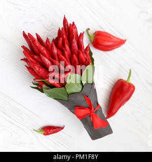 Kleines Bouquet von hot chili peppers in der Form eines Herzens auf eine weiße Holztisch Stockfoto