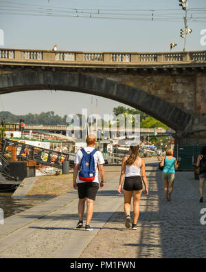 Zwei junge Menschen zu Fuß über einen Fußweg entlang des Flusses Vltava im Zentrum von Prag. Stockfoto