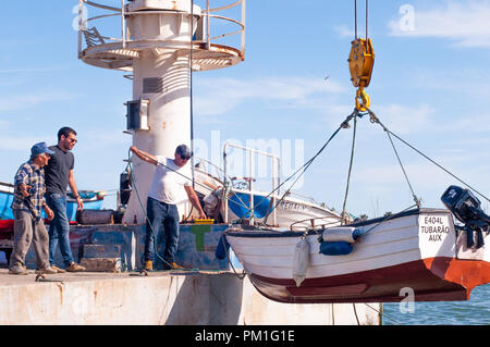 Männer heben Fischerboot in Wasser mit Bootskran setzen Stockfoto