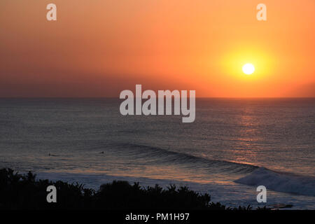 Surfer beobachten die Sonne über dem Horizont, von Uvongo, Südafrika Stockfoto