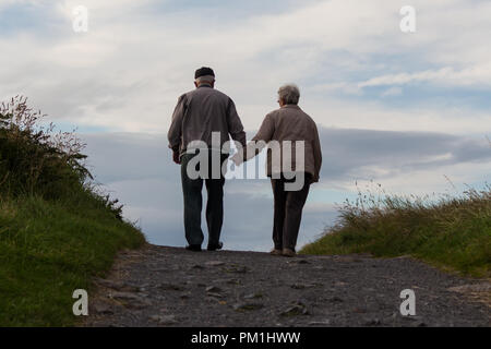 Ein älteres Ehepaar gemeinsam erklimmen einen Hügel Stockfoto
