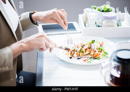 Seitenansicht Nahaufnahme des unkenntlich junge Frau schneiden schöne Teller und genießen Sie das Frühstück im Cafe, kopieren Raum Stockfoto