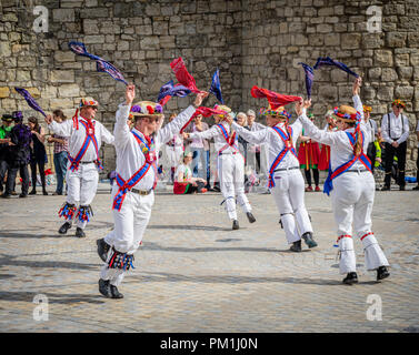 Eine Gruppe von weiblichen und männlichen Morris-Tänzern führt einen Morris-Tanz vor den historischen Mauern von Southampton, Southampton, Hampshire, England, Großbritannien, auf Stockfoto