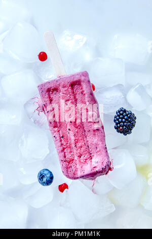 Gefrorene Heidelbeeren Smoothies auf einem Stock auf Eiswürfel mit verschiedenen Beeren vorgestellt. Diätetische Sommer Nachtisch. Flach Stockfoto