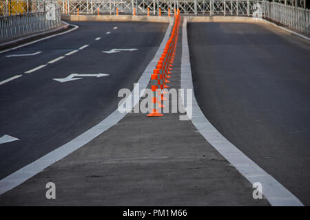 Eine Linie der Sicherheit Verkehr Kegel in der Mitte einer Straße mit weißen Linien und Pfeile Stockfoto