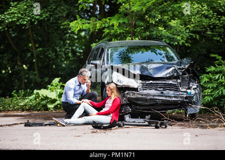 Junge Frau mit dem Auto nach einem Unfall und ein Mann einen Anruf tätigen. Stockfoto