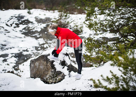 Eine ältere Frau runner Schnürsenkel binden im Winter Natur. Stockfoto