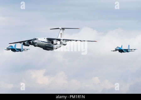 Eine Iljuschin Il-76-Transportflugzeuge der Ukrainischen Luftwaffe wird von zwei Suchoi Su-27-Kampfjets eskortiert. Stockfoto