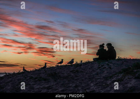 Adelaide Australien. 17.September 2018. Leute, die sich einen schönen Sonnenuntergang auf Grange Strand mit einem dramatischen Himmel und Farben Credit: Amer ghazzal/Alamy leben Nachrichten Stockfoto