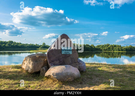 Riesige Steine am Ufer. Die Inschrift auf der Platte: Das Dorf Pervomayka wurde 1929 gegründet. Stockfoto