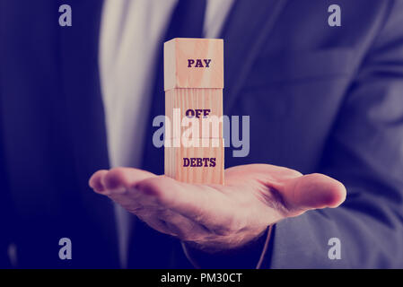 Retro Image mit einem Geschäftsmann mit einem von drei Holzwürfel auf seinem Palm angezeigte Text aus Schulden ausgeglichen. Stockfoto