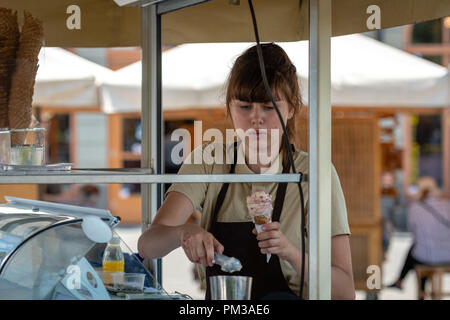 RIGA, Lettland - 31. JULI 2018: Ice Cream Verkäufer setzt Eis in der Waffel Cup. Stockfoto
