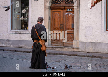 RIGA, Lettland - 31. Juli 2018: der Mann, der in den mittelalterlichen Kleidern in der Altstadt auf der Straße versorgt die Tauben. Stockfoto