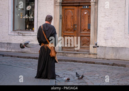 RIGA, Lettland - 31. Juli 2018: der Mann, der in den mittelalterlichen Kleidern in der Altstadt auf der Straße versorgt die Tauben. Stockfoto