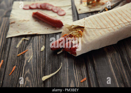 Geräucherte Wurst in pita Brot auf hölzernen Hintergrund Stockfoto