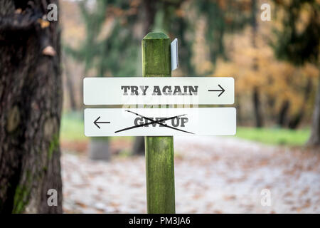 Schild mit zwei Zeichen sagen - versuchen Sie es erneut - bis Geben - das Zeigen in entgegengesetzte Richtungen mit dem Schild oben Geben durch gekritzelt. Stockfoto