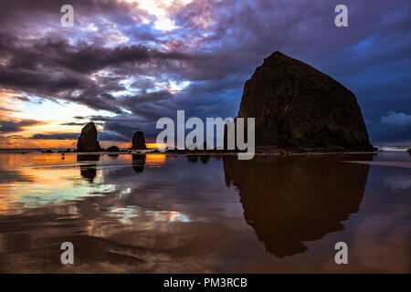 Des Oregon Haystack Rock entlang Cannon Beach am Abend Stockfoto