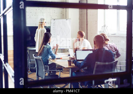 Arbeiten hart, um zu gewinnen. Geschäftsfrau, die Durchführung einer Präsentation mit Flipchart, während in der kreativen Arbeiten im Büro. Stockfoto