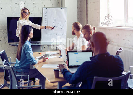 Arbeiten hart, um zu gewinnen. Geschäftsfrau, die Durchführung einer Präsentation mit Flipchart, während in der kreativen Arbeiten im Büro. Stockfoto