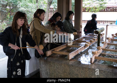 Menschen und Touristen während des traditionellen Handwäsche Zeremonie vor dem Betreten der Meiji Jingu oder Meiji Jingo Schrein in Tokio, Japan, Asien Stockfoto